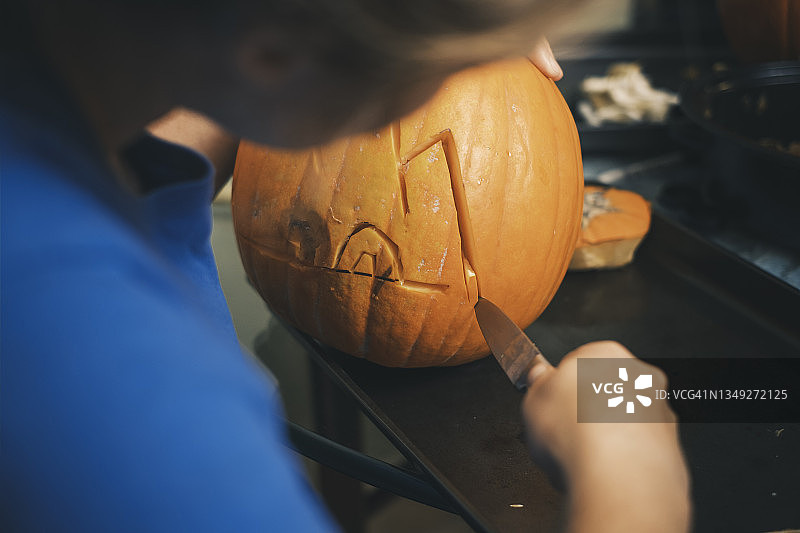 女子雕刻万圣节南瓜的肩部视角图片素材