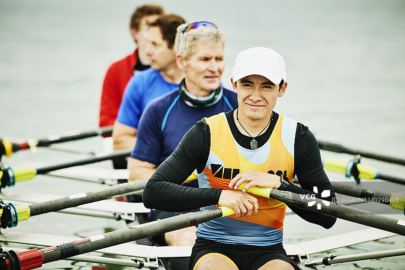 微笑男赛艇运动员在训练前与队友坐在单人双桨赛艇上图片素材