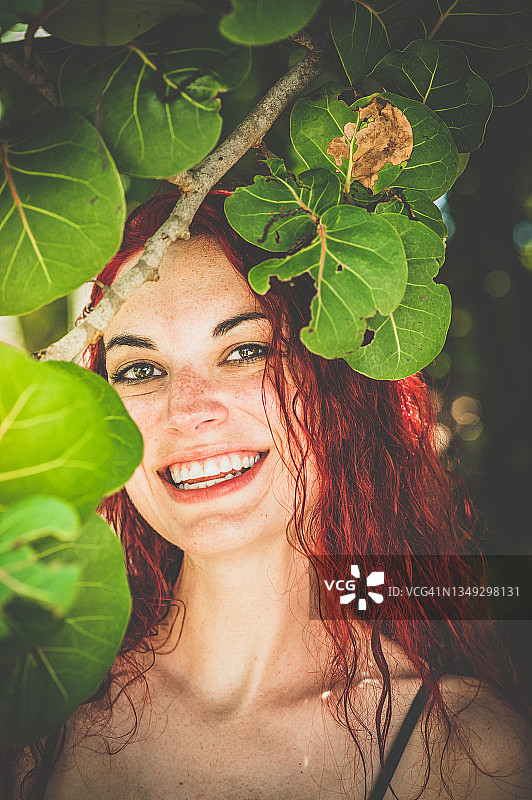 热带风情夏日写真：美丽的红发年轻女人图片素材