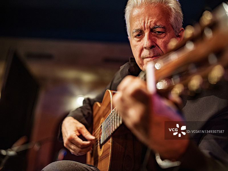 年长的男吉他手在舞台上演奏古典吉他图片素材