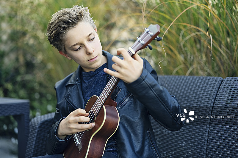 小男孩在阳台上弹尤克里里图片素材