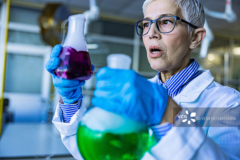震惊的高级化学家在实验室研究化学物质。图片素材
