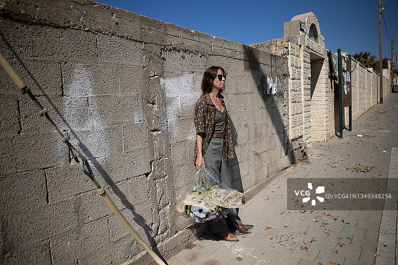 女人靠在墙上，手里拿着一束干花图片素材