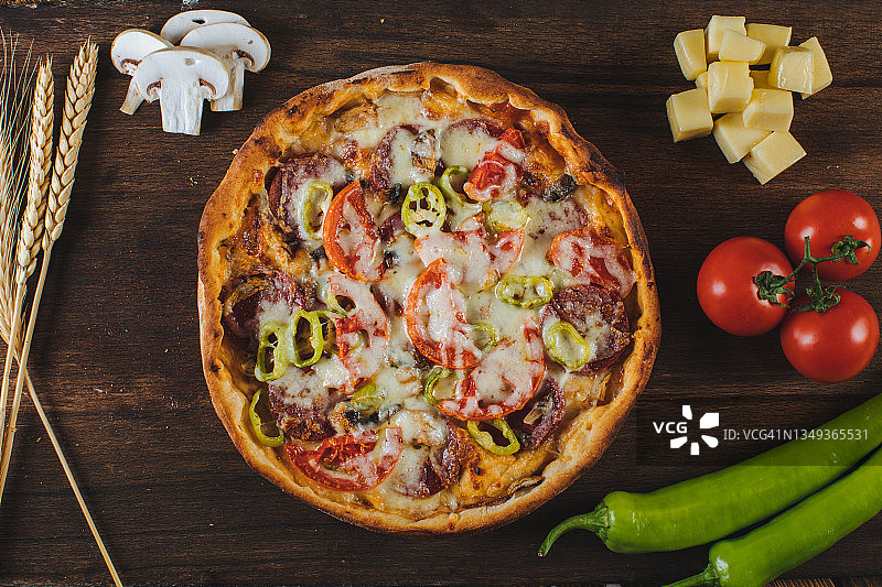 乡村风披萨，配萨拉米香肠、火腿、培根、大蒜和新鲜香草图片素材