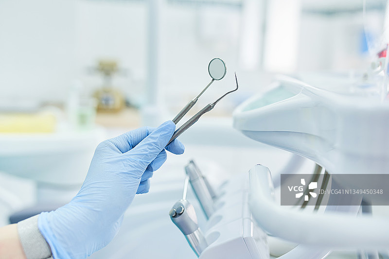 戴防护手套的女人手中的牙医器械特写图片素材