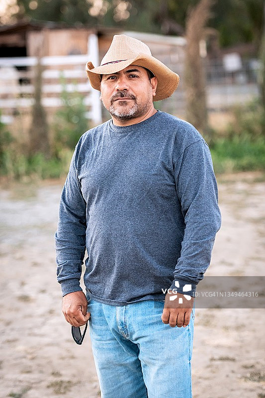 戴着牛仔帽的沉思的西班牙裔中年男子看着镜头图片素材