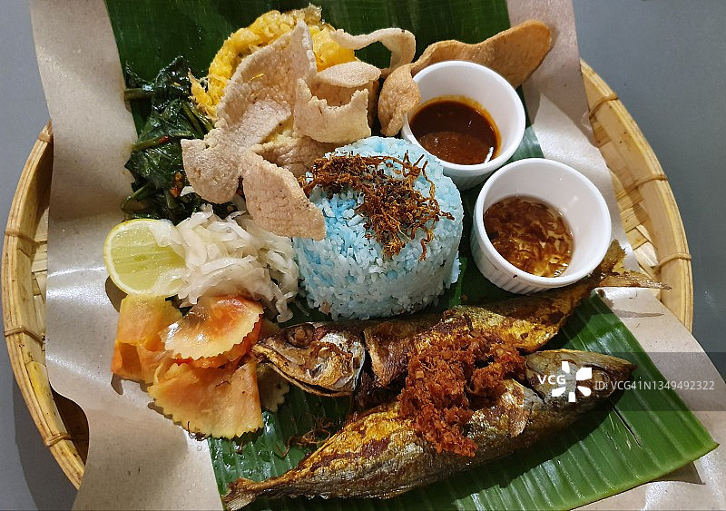 Nasi Kerabu蓝米饭配炸鱼、沙拉和鱼饼图片素材
