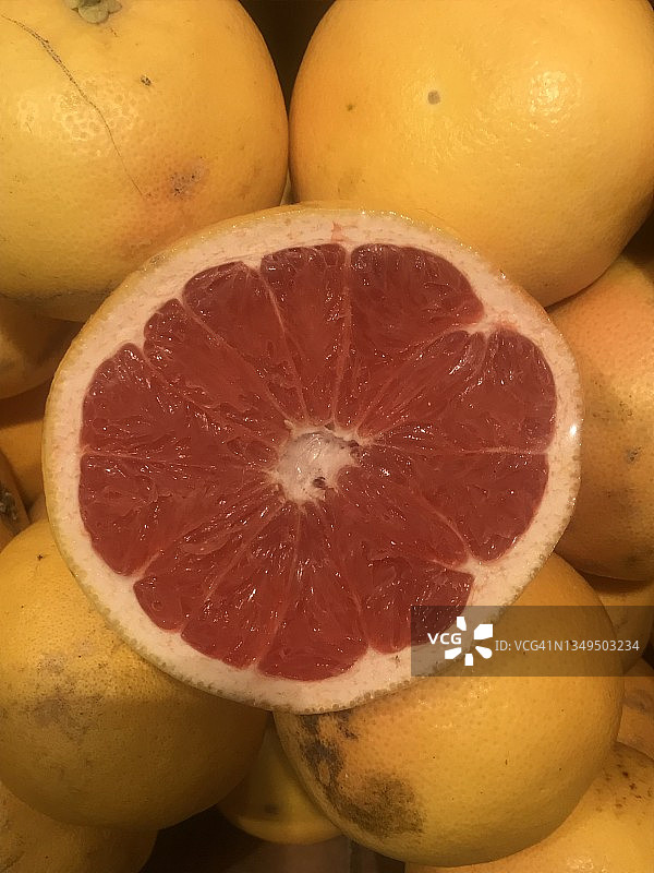 市场摊位上堆放的柑橘类水果，新鲜有机葡萄柚，热带水果堆，红色和粉红色分段水果的横截面，酸味多汁的红宝石柚图片素材