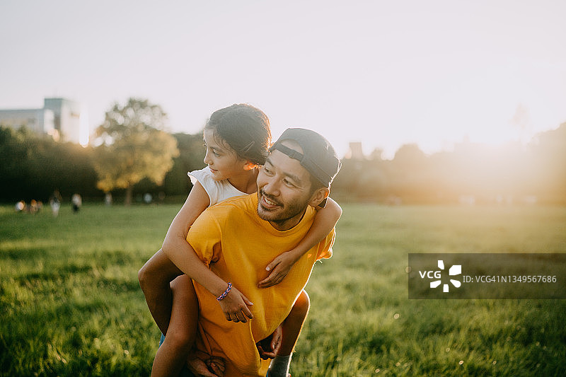快乐的父亲在东京日落时分的公园里抱着小女儿图片素材