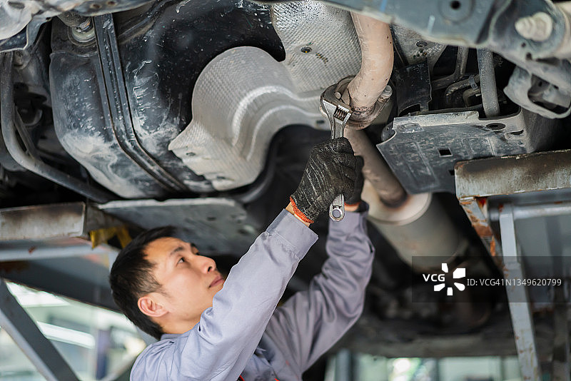 亚洲男维修工检查车底图片素材
