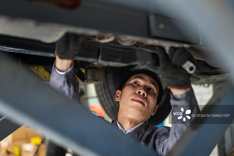 亚洲男维修工检查车底图片素材