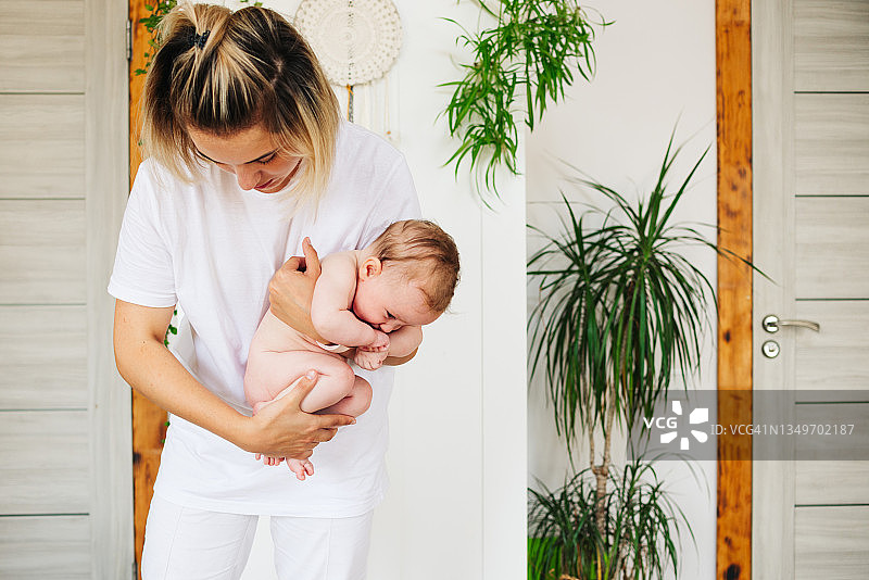 年轻女孩为婴儿按摩，儿科健康概念图片素材
