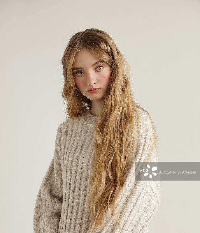 身穿米色毛衣的年轻漂亮女人图片素材