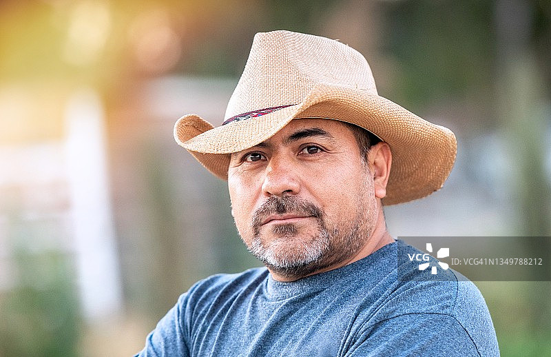 戴着牛仔帽的沉思的西班牙裔中年男子看着镜头图片素材