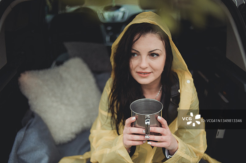 一位快乐的年轻女子穿着黄色雨衣，在雨天于树林里享受大自然图片素材