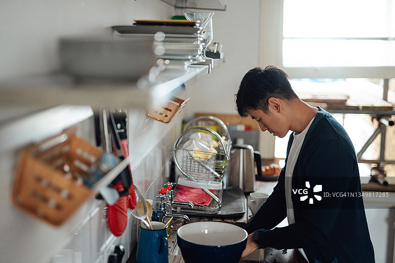 年轻的亚洲男子在厨房洗碗图片素材