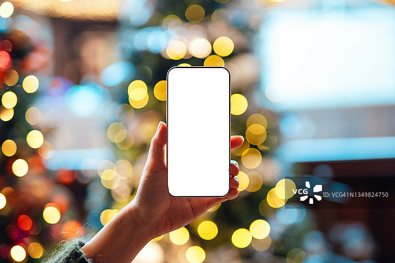 女性手持智能手机与散景背景特写图片素材