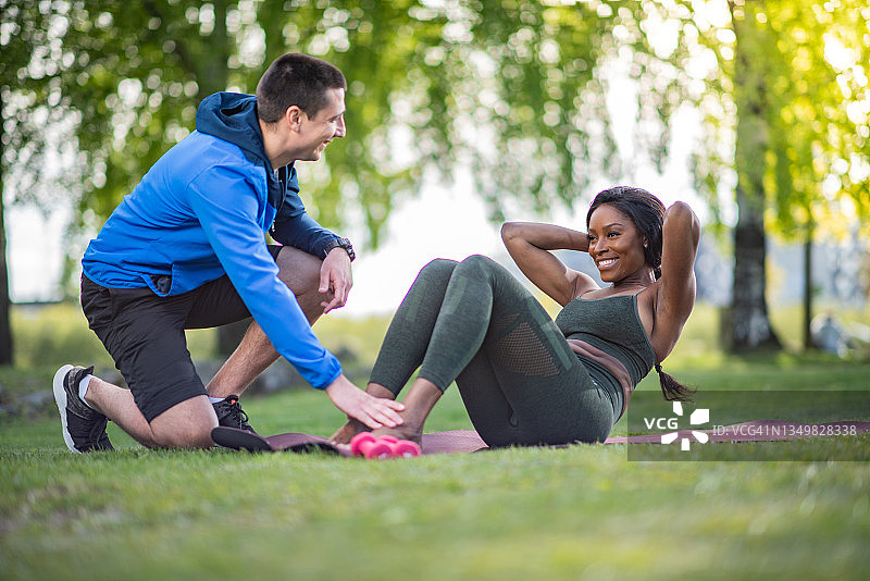 在朋友的帮助下做仰卧起坐的女人图片素材