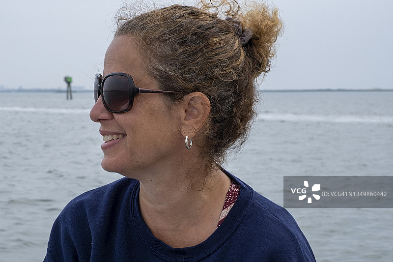 戴着太阳镜，坐在摩托艇上的40多岁女子侧面照图片素材