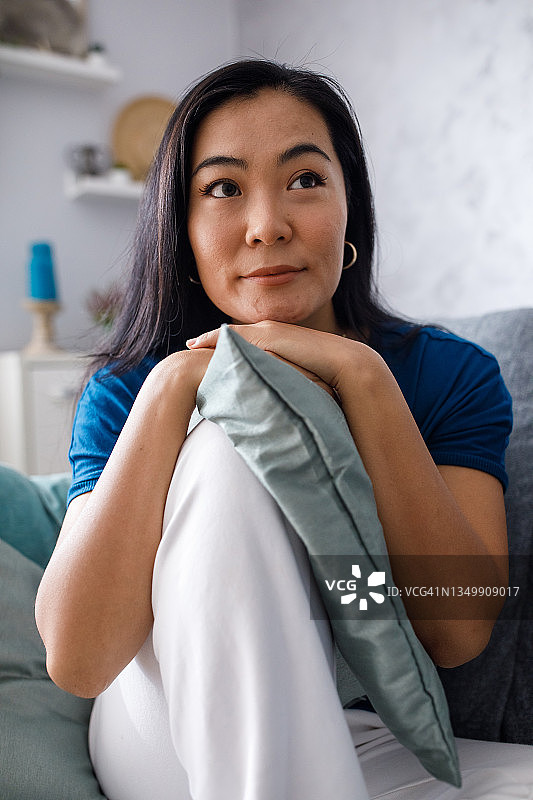 托着头，面带微笑沉思的美丽年轻女人图片素材