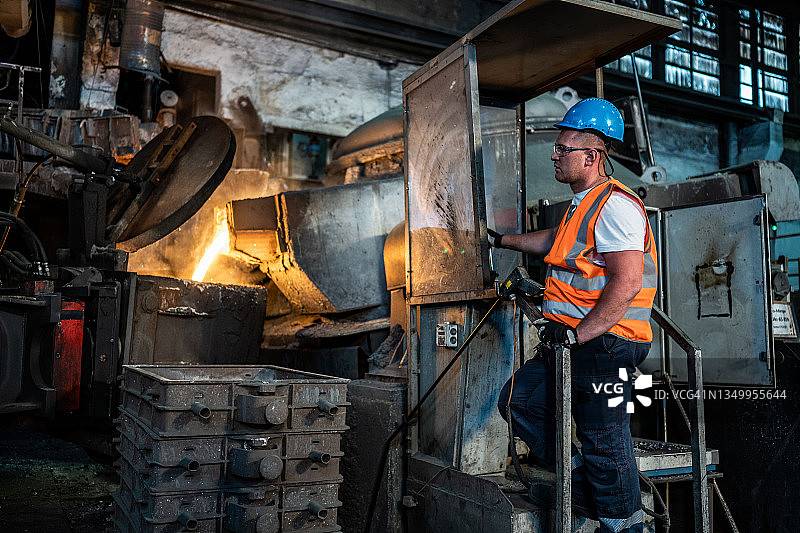 将加热炉中的热金属液体倒入钢厂的容器中图片素材