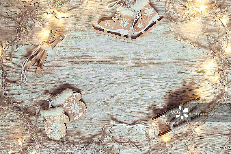 浅色木质背景上的小木制圣诞玩具（溜冰鞋、滑雪板、手套、雪橇），顶视图。新年贺卡和圣诞节。2022年，数字22图片素材