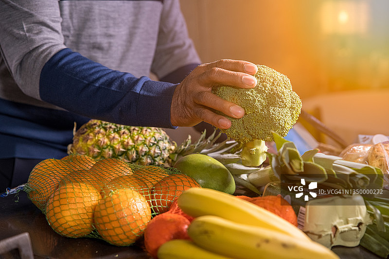 年长的男人在厨房的柜台上放着杂货、水果和蔬菜图片素材