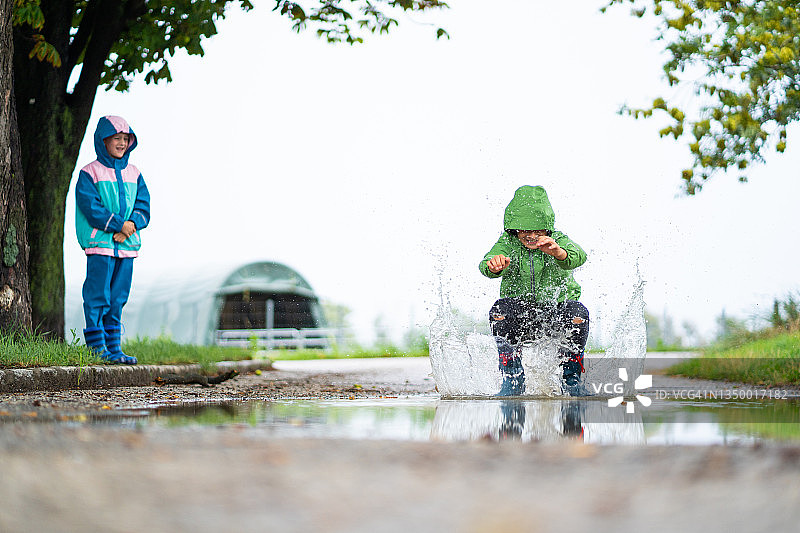 孩子们在雨中水坑里玩耍图片素材