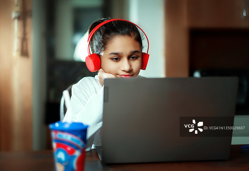 戴着耳机用笔记本电脑上网课的快乐女学生图片素材