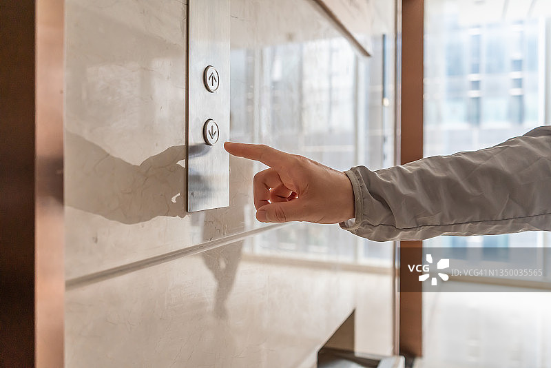 手在电梯门前准备按下向下按钮图片素材
