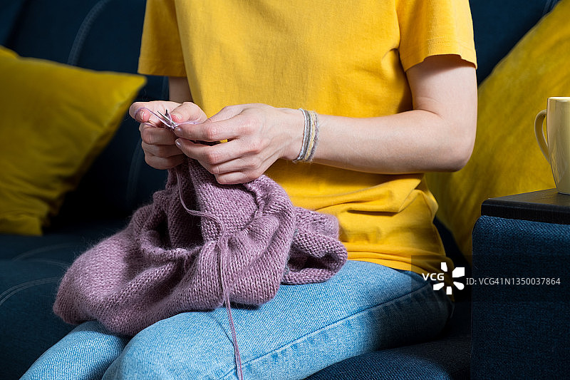 女孩拿着针织品和金属针织针的特写图片素材