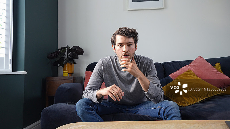 在沙发上表情震惊的年轻男人图片素材