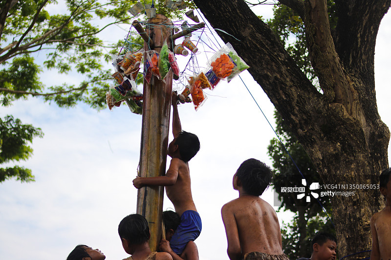 一群快乐的印度尼西亚儿童在印度尼西亚独立日玩名为“Panjat Pisang”的传统游戏，满身泥泞图片素材