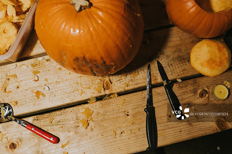 木桌上完整的成熟橙色南瓜和刀具图片素材