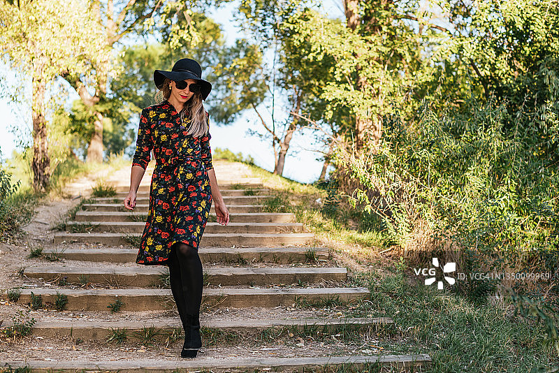 戴复古黑色帽子和连衣裙的漂亮女人在秋天的公园里图片素材