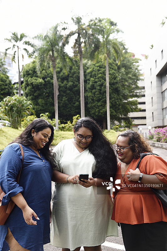 三名新加坡女性正在观看手机视频图片素材