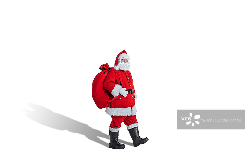 圣诞老人带着礼物袋在白色背景上行走图片素材