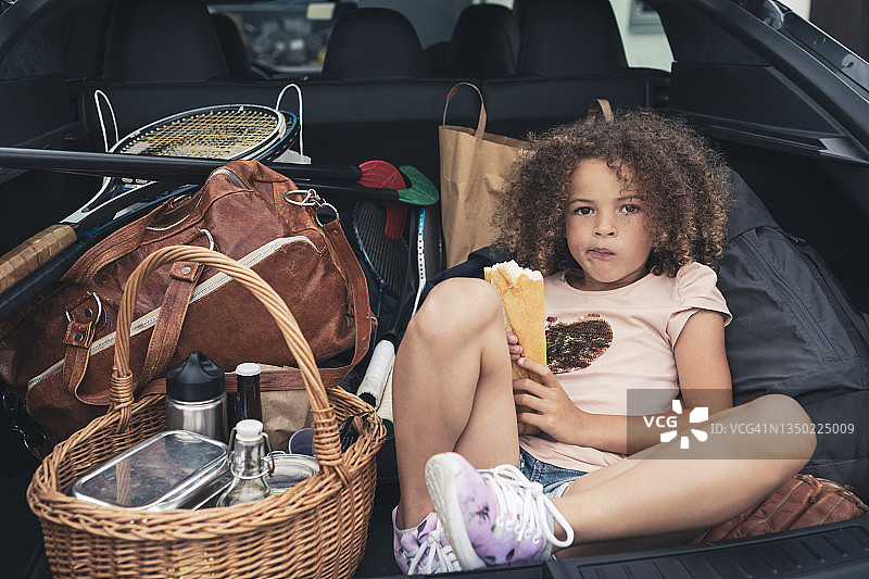 坐在后备箱行李旁吃面包的女孩肖像图片素材