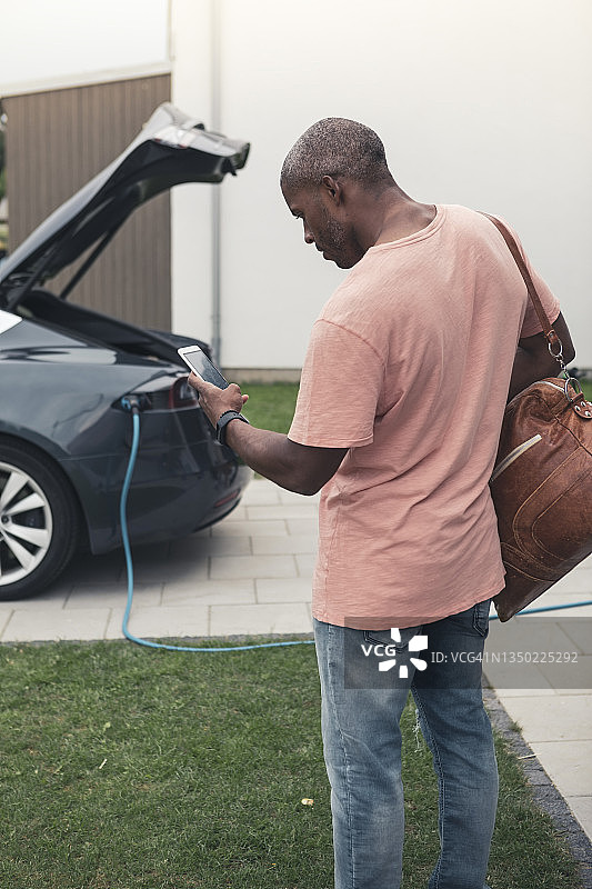 男子在充电站使用智能手机的背影图片素材