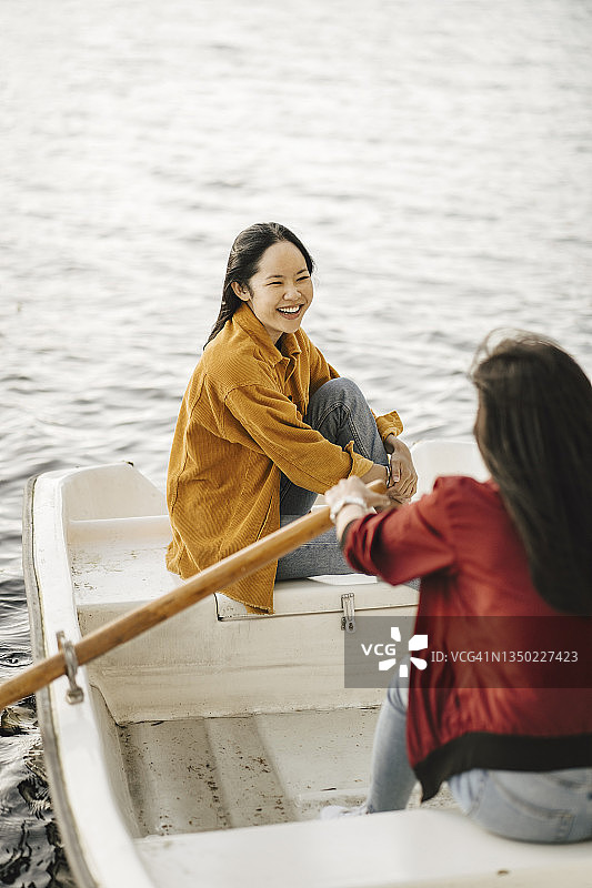 看着划船的女朋友的快乐年轻女人图片素材