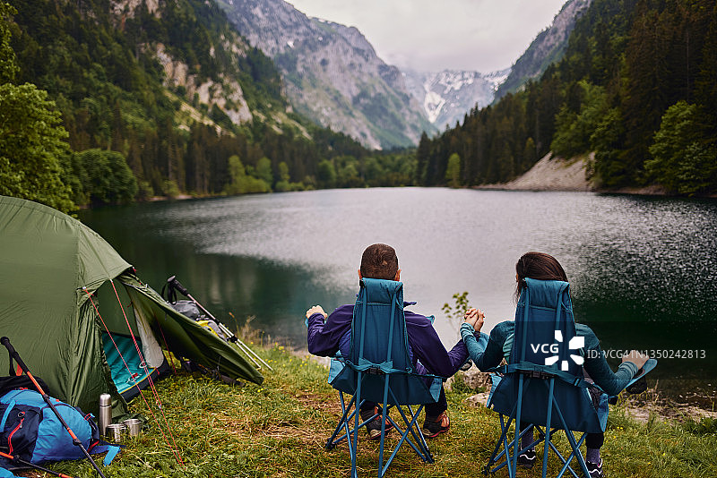 在湖边露营时坐在帐篷外露营椅上的放松情侣图片素材