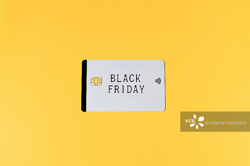 黄色背景上带有“黑色星期五”字样的白色信用卡。黑色星期五、购物、商业和信用卡概念。图片素材