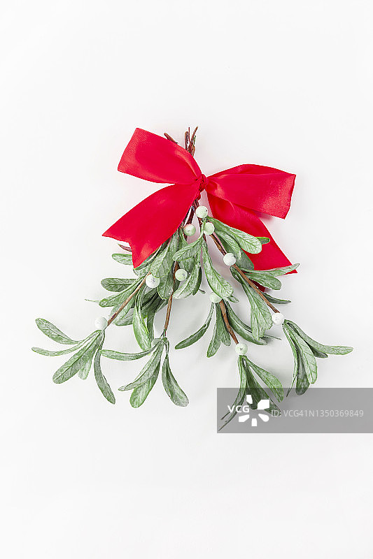白色背景上的圣诞槲寄生枝条与红色丝带蝴蝶结，圣诞新年概念图片素材