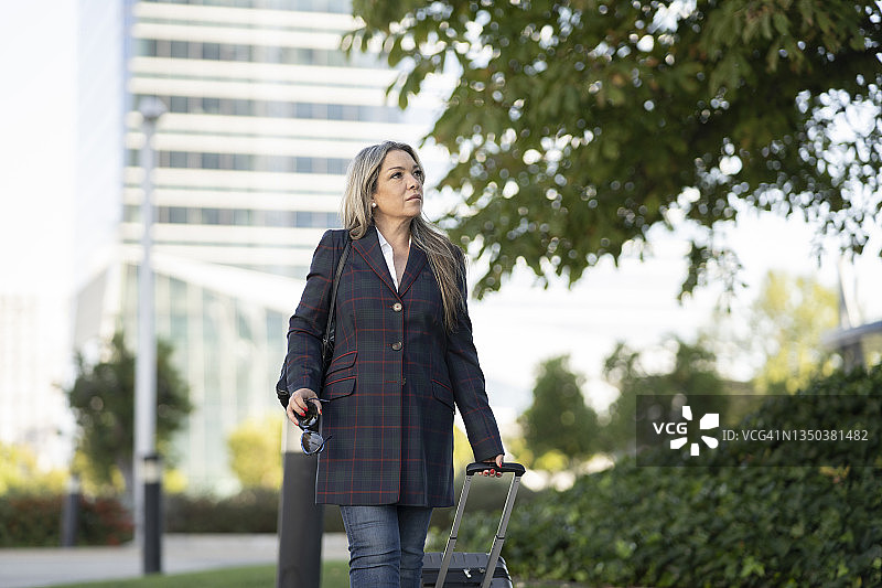 在城市里旅行的带行李箱的金发中年妇女图片素材