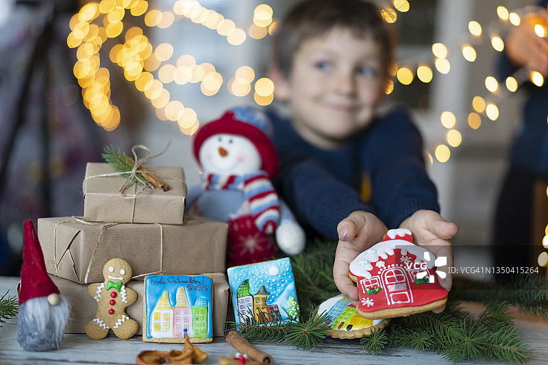 小男孩拿着姜饼屋，桌上堆满了棕色包装的礼物图片素材
