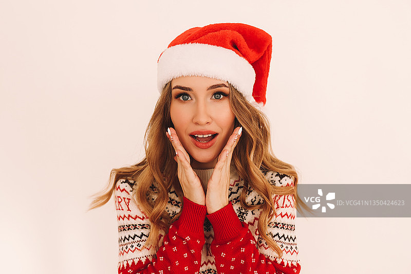 特写：戴圣诞帽的女孩在白色背景中惊讶的表情，留有文字空间图片素材