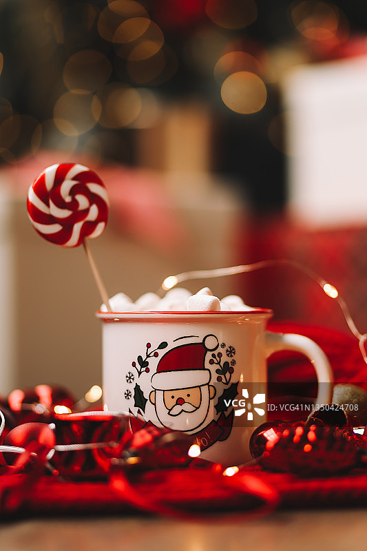 圣诞图片：舒适的热咖啡杯，棉花糖和糖果，在新年冬日假期期间，红色针织毯上摆放着圣诞树玩具和礼品盒图片素材