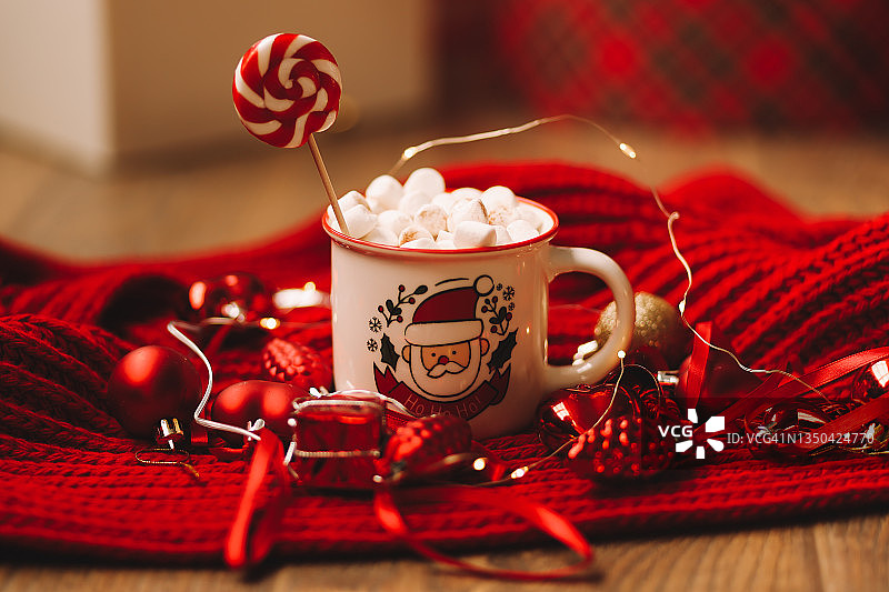 圣诞图片：舒适的热咖啡杯，棉花糖和糖果，在新年冬日假期期间，红色针织毯上摆放着圣诞树玩具和礼品盒图片素材
