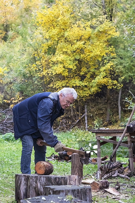 年长的男人用斧头砍木头图片素材