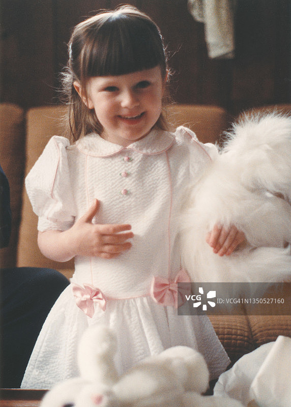童年天真：小女孩抱着毛绒玩具，20世纪80年代的孩子笑着拿着玩具，80年代的复古照片图片素材